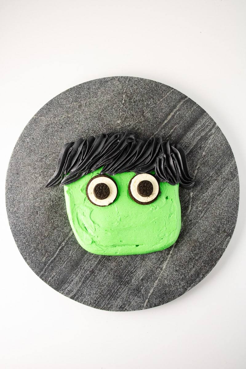 Sandwich cookie eyes with mini cookie pupils added to a Frankenstein buttercream face
