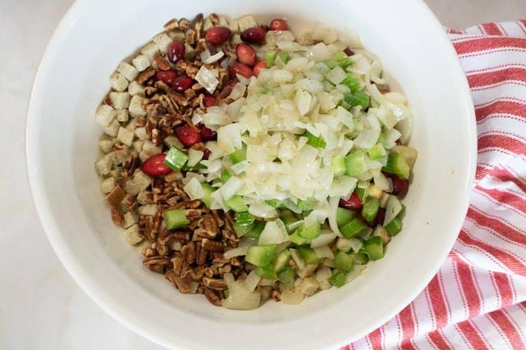 All of the ingredients for Instant Pot Cranberry Pecan Stuffing combined in a large white mixing bowl