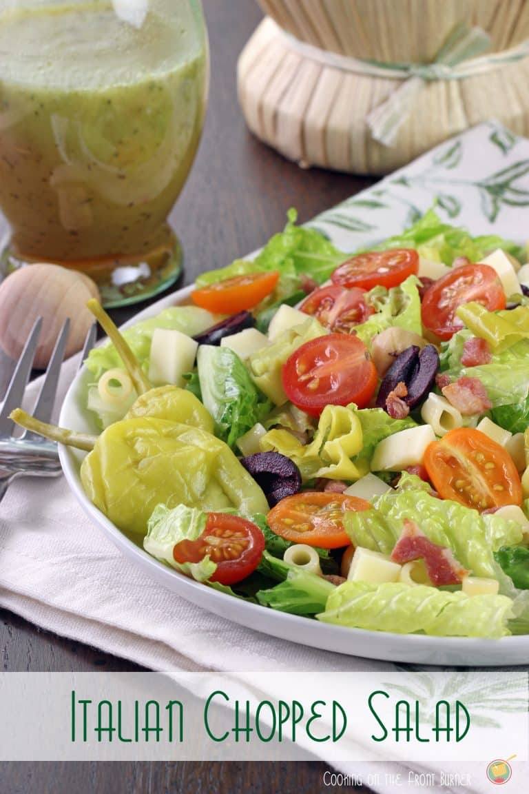 Italian chopped salad on a white plate with a jar of homemade Italian dressing in the background