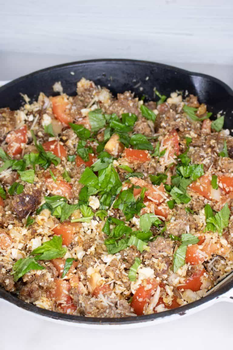 Italian sausage, cauliflower rice, tomatoes, onions and lettuce cooked together in an iron skillet