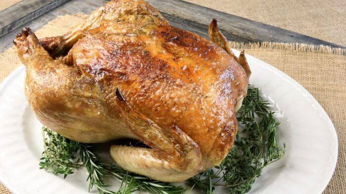 keto chicken sitting on herbs on a white plate on a countertop