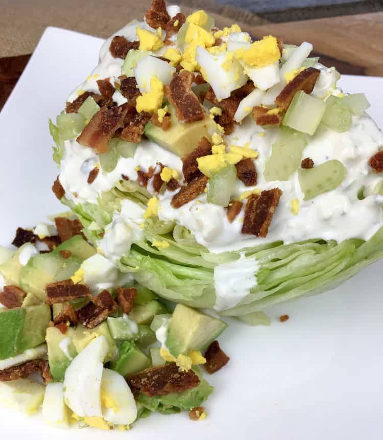 closeup of keto salad wedge with avocados, eggs, and blue cheese dressing