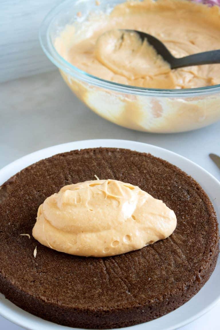 Chocolate cake layer on a plate with a dollop of pumpkin cream cheese filling in the center
