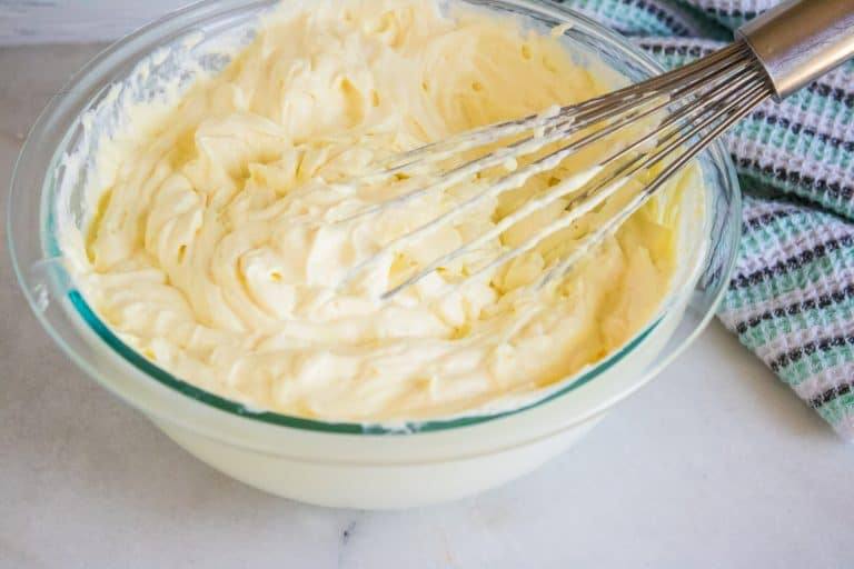 ingredients for Lemonade No-Churn Ice Cream being folded together with a large whisk inside a clear glass mixing bowl