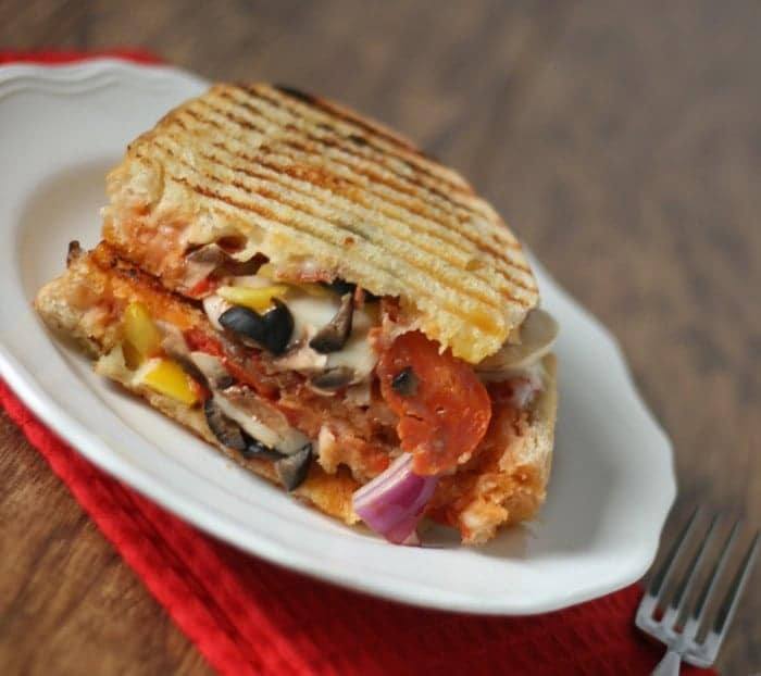 Close-up of a pressed pizza grilled cheese with pepperoni, black olives, mushrooms and red onion