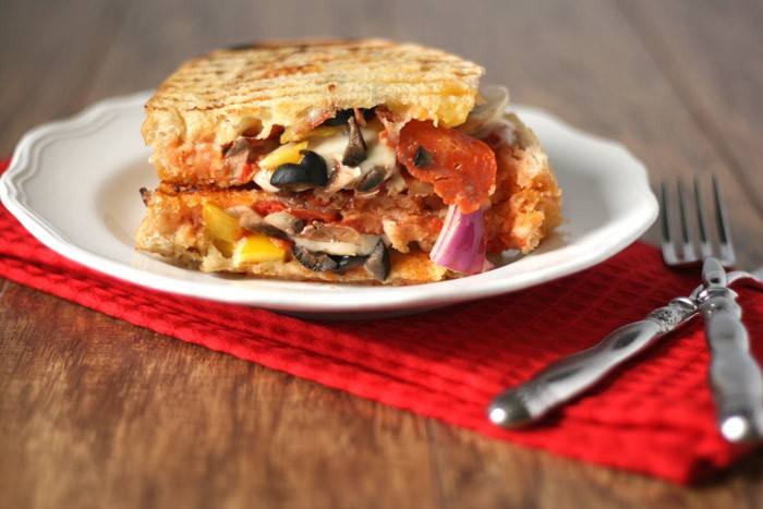 Loaded pizza grilled cheese sandwich stuffed with pepperoni, veggies and melted mozzarella on a plate