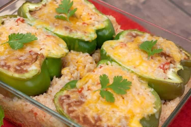 Baked stuffed pepper halves with melted cheese nestled in Mexican rice