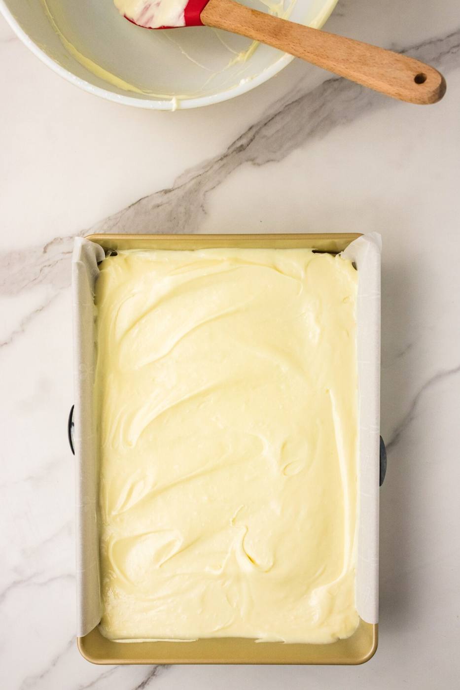 Cream cheese topping spread over the cake mix crust in a baking pan before baking