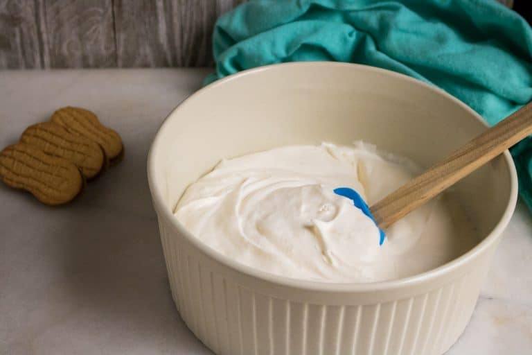 Nutter Butter No-Churn Ice Cream base in a bowl with whole nutter butter cookies beside the bowl and a blue napkin