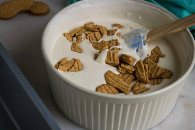 Ice cream base with broken up pieces of nutter butter cookies being stirred in.