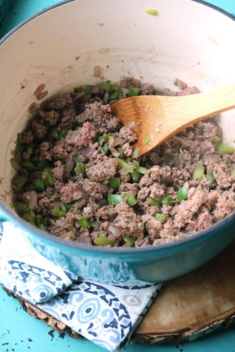 Stirring the browned beef and vegetables together with a wooden spoon