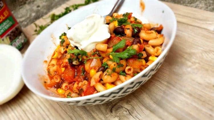 Bowl of southwest chili mac with black beans, corn, sour cream and cilantro