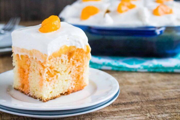 A slice of Orange Creamsicle Poke Cake served on a white dessert plate