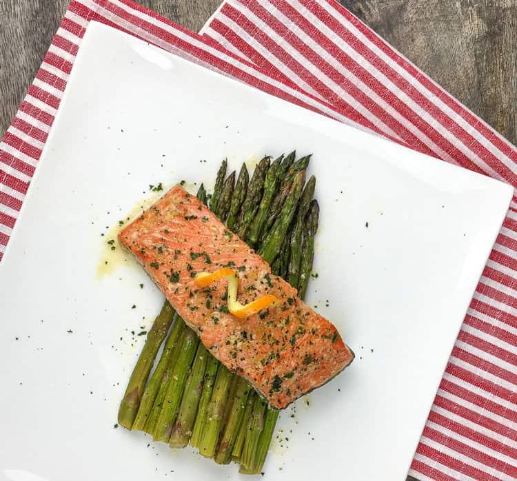 salmon plated over asparagus on white square plate