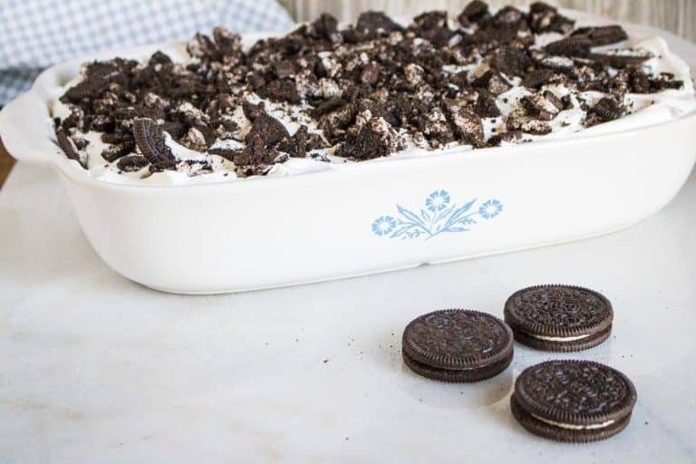 13x9 white corning ware pan showing finished oreo poke cake with whipped topping and crushed oreos on top