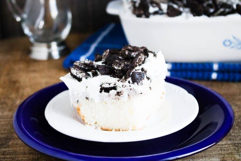 blue liner plate with white plate on it holding finished piece of oreo poke cake corning ware pan is in background