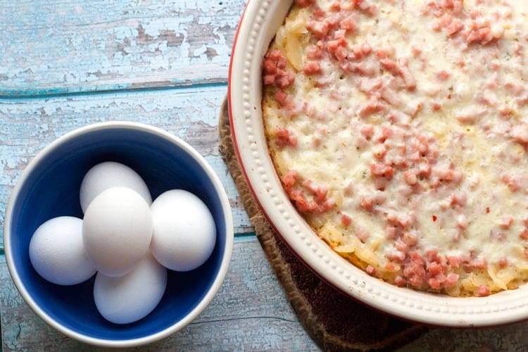 Southwest breakfast casserole in a baking dish beside a bowl of eggs