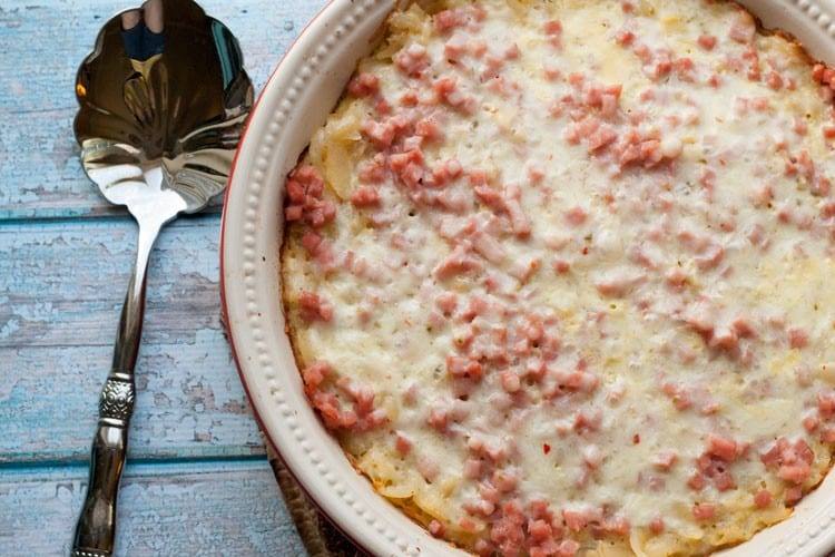 Baked southwest breakfast casserole with ham and melted pepper jack cheese next to a serving spoon
