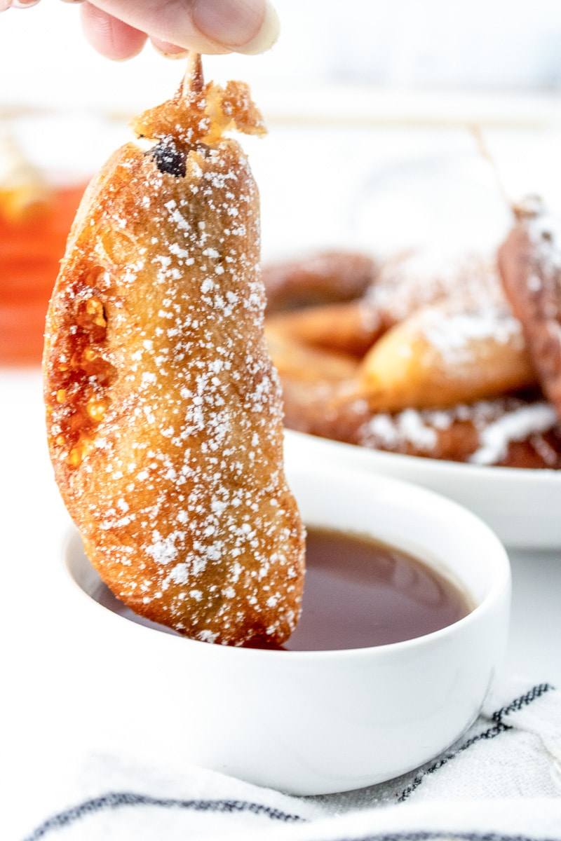 homemade pancakes and sausage on a stick, being dipped in maple syrup