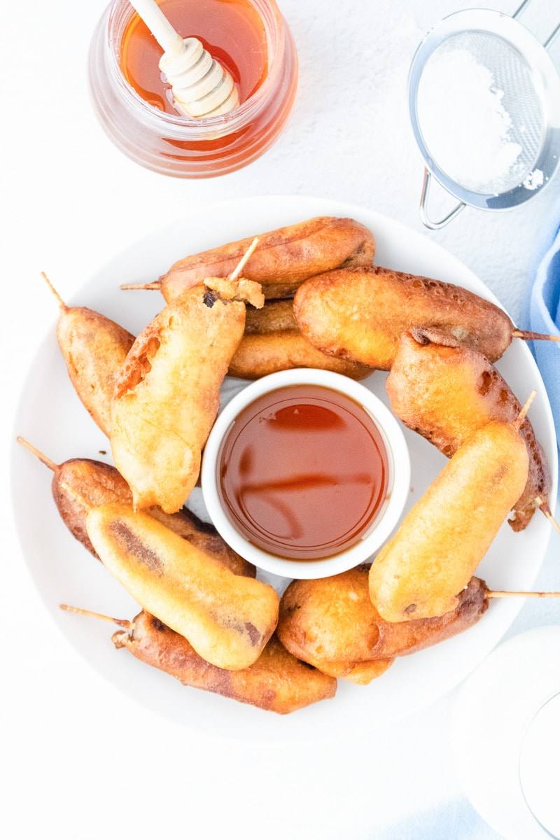 white plate with the cooked pancakes and sausages on sticks