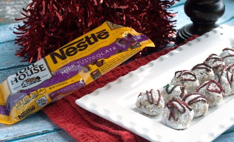 Peppermint snowball cookies on a white platter next to bags of milk chocolate morsels