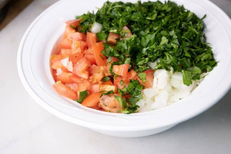 Chopped tomato, chopped onion and fresh cilantro in a white serving bowl