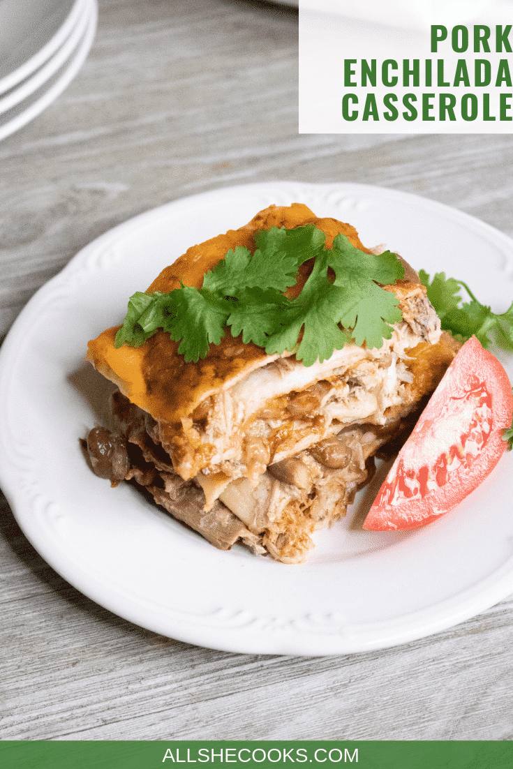 Serving of Pork Enchilada Casserole on white plate with tomato wedge garnish.