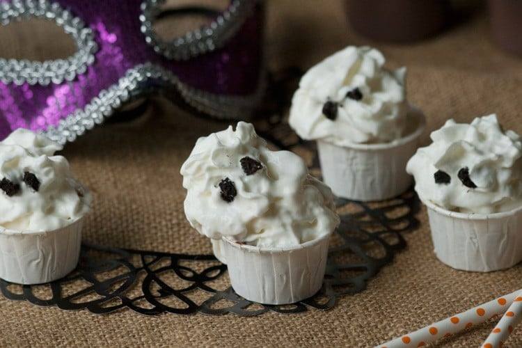 Halloween pudding shots topped with whipped cream ghosts with Oreo eyes