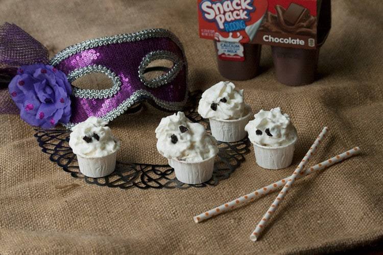 Halloween pudding shots with whipped cream ghosts, a purple masquerade mask and Snack Pack chocolate pudding