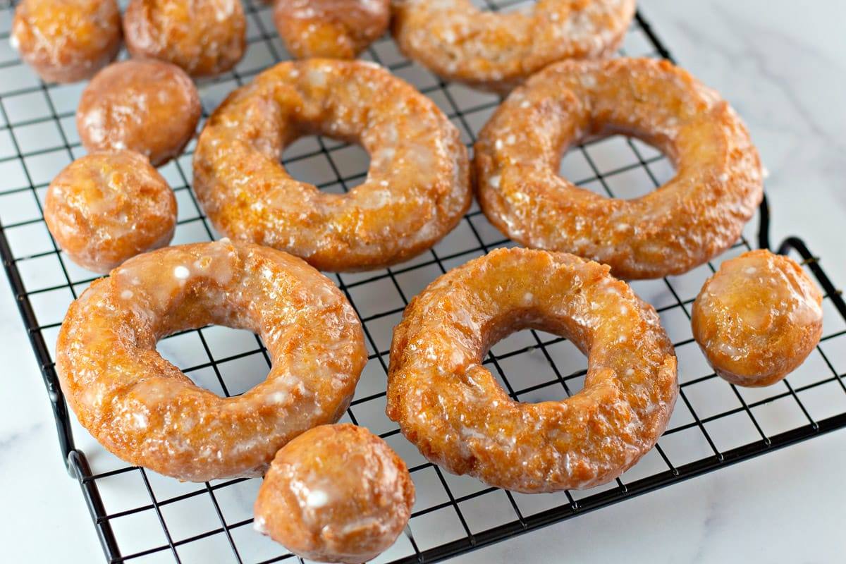 Pumpkin donuts and donut holes cooling on a wire rack