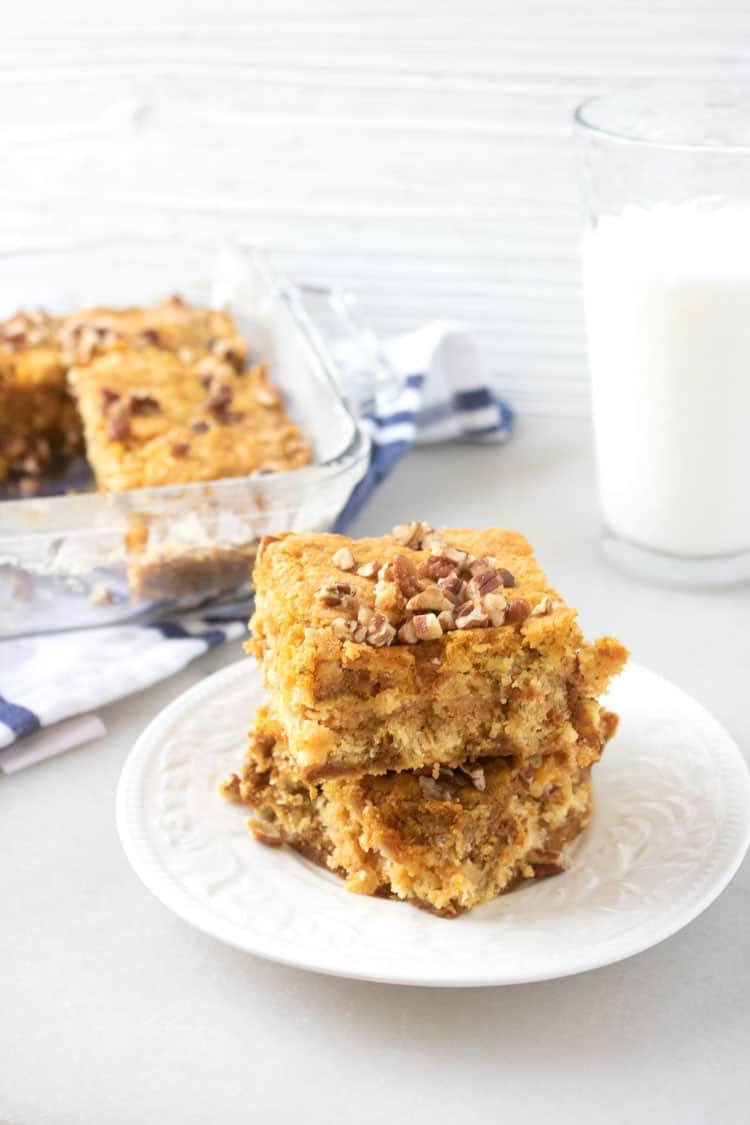 pumpkin dump cake on a white plate with a glass of milk and cake in pan in the background