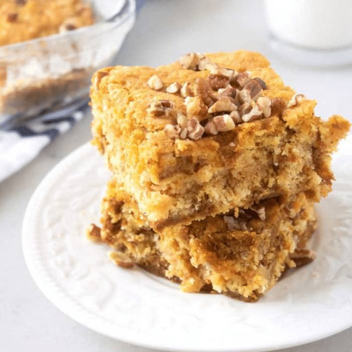 Pumpkin dump cake squares topped with pecans stacked on a white plate