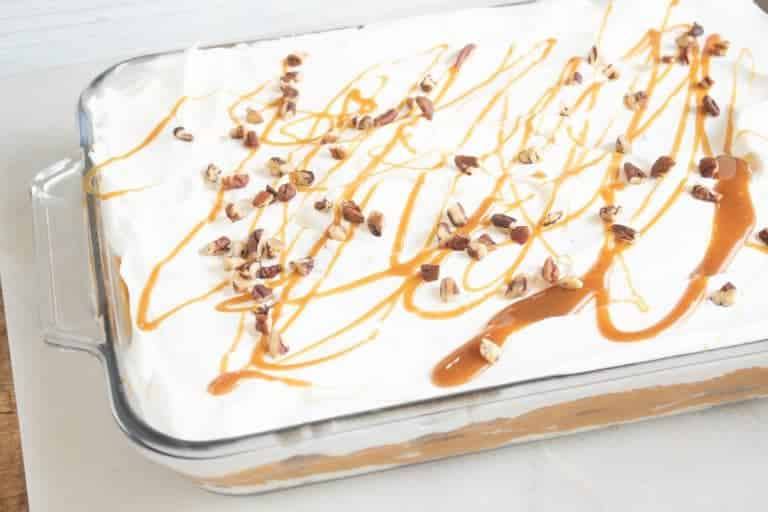 No-bake pumpkin lasagna dessert in a 9x13 glass baking dish, drizzled with caramel and sprinkled with pecans