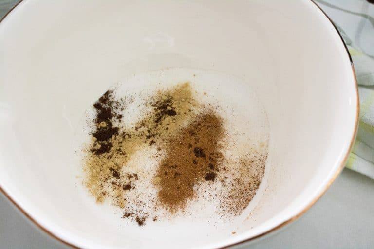 Sugar, cinnamon, ginger, cloves, and salt for pumpkin meringue pie in a white ceramic bowl