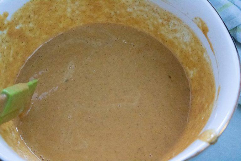 Smooth pumpkin pie filling mixed in a white bowl with a green spatula