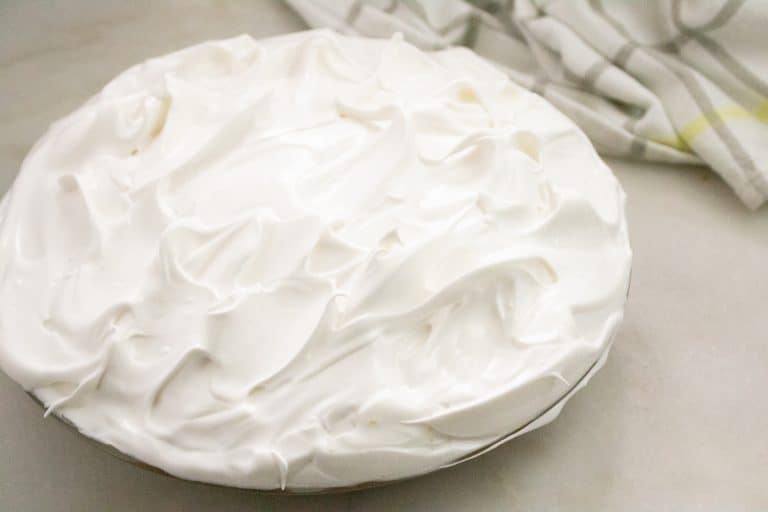 Unbaked meringue spread over pumpkin pie and sealed to the crust