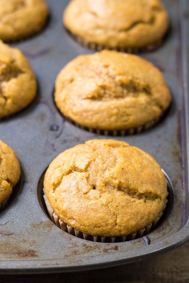 Close-up of domed pumpkin muffins in a metal muffin tin before glazing