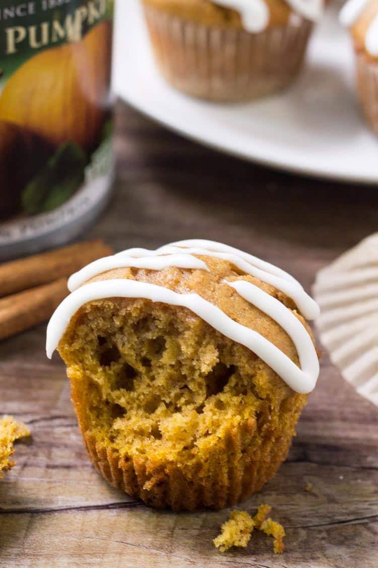 A pumpkin muffin topped with cream cheese glaze, with a bite taken out