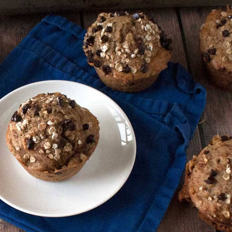 Overhead view of pumpkin chocolate chip muffins topped with oats on a blue napkin