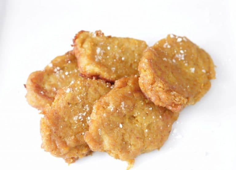Overhead view of homemade pumpkin patties dusted with powdered sugar on a white plate