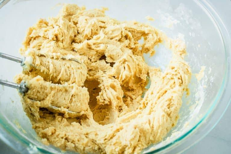 Creamed pumpkin snickerdoodle cookie dough in a glass mixing bowl with beaters