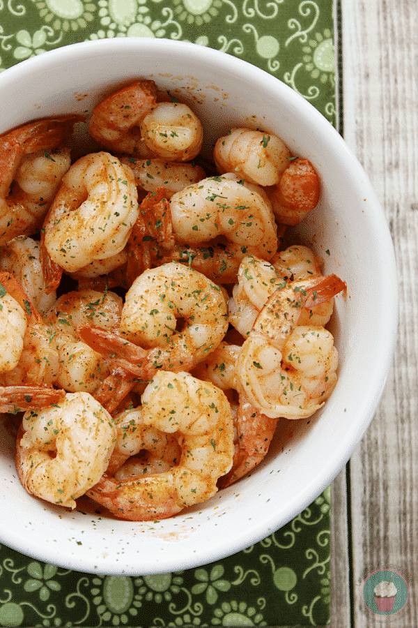 Cajun shrimp tossed in butter and seasoning in a white bowl, garnished with chopped parsley