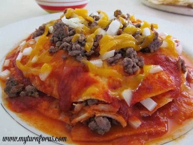 Stacked red enchiladas Chihuahua style with red chile sauce, ground beef, cheddar cheese and chopped onion