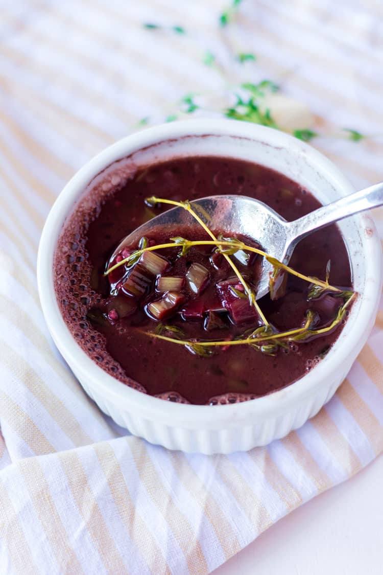 white ramekin with red wine steak sauce and a spoon resting in the bowl