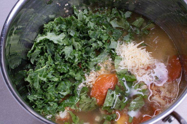 Chicken stock added to roasted cauliflower rice, tomatoes, kale, basil and Parmesan in a stock pot