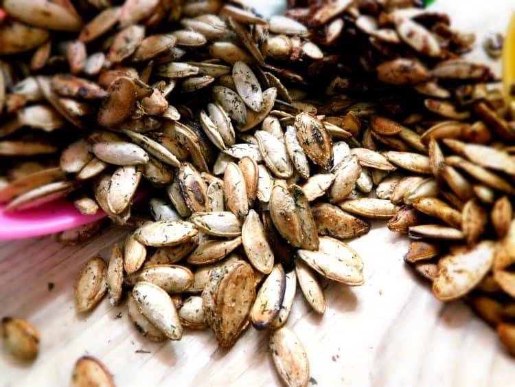 Close-up of dill and vinegar roasted pumpkin seeds on a wooden board
