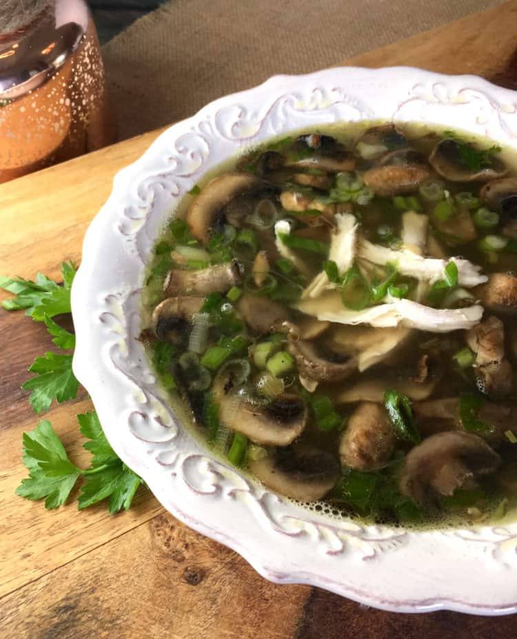 Chicken marsala soup with sliced mushrooms, shredded rotisserie chicken and green onions in a white scalloped bowl