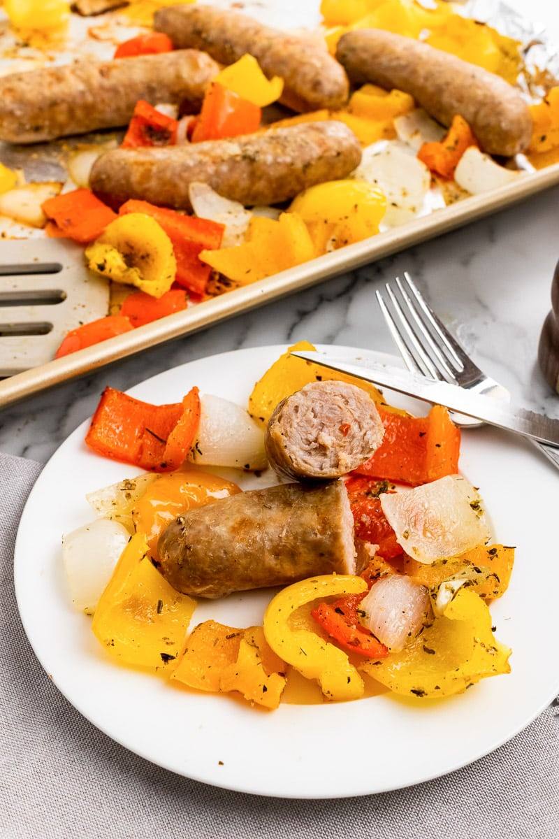 plate of sheet pan italian sausage and peppers next to baking sheet