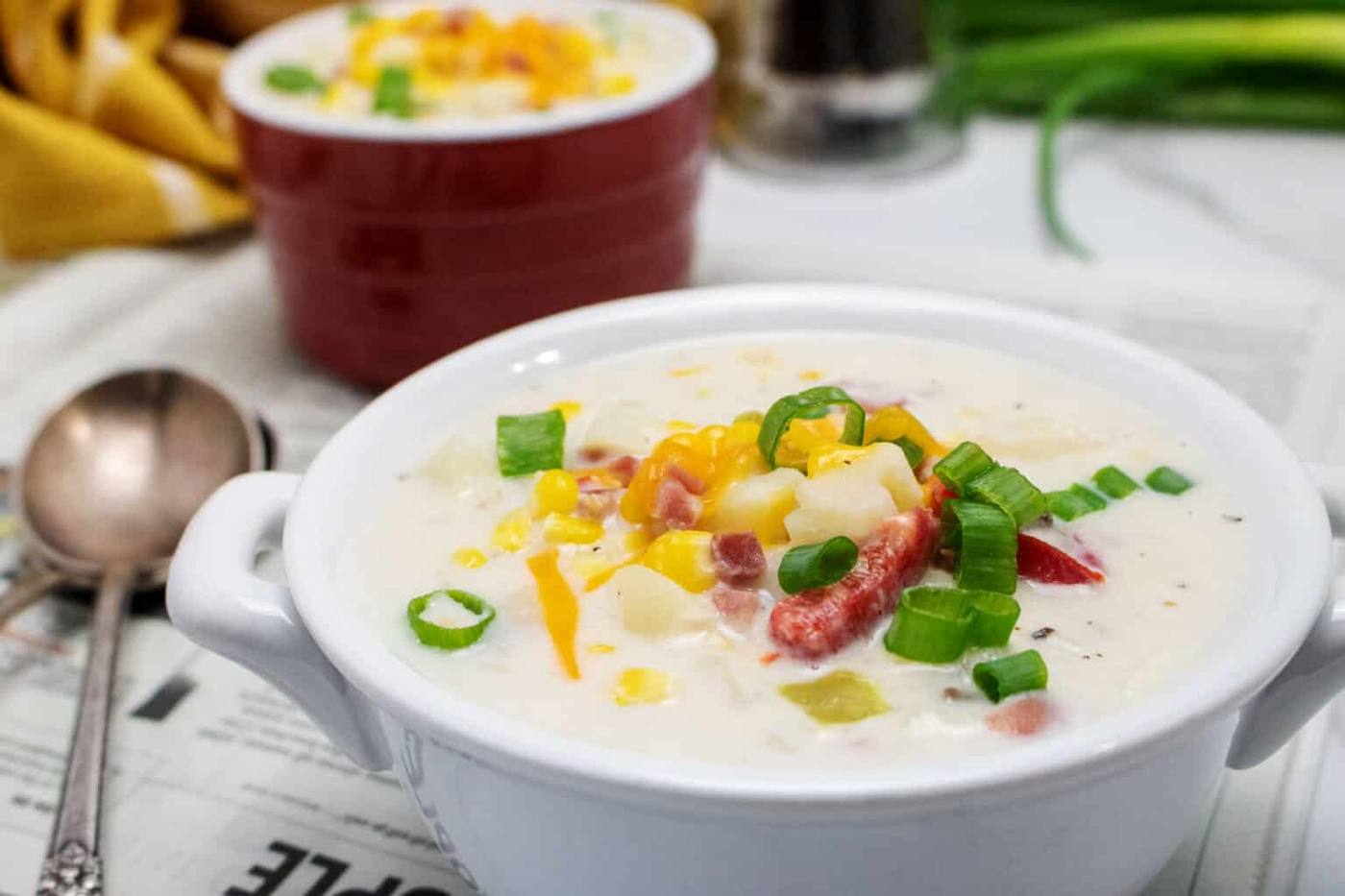 Creamy slow cooker corn chowder with ham, corn and green onions in a white bowl