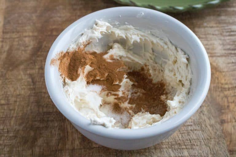 the snickerdoodle crepes recipe cream cheese filling mixture ingredients in a white bowl sitting on a wood table
